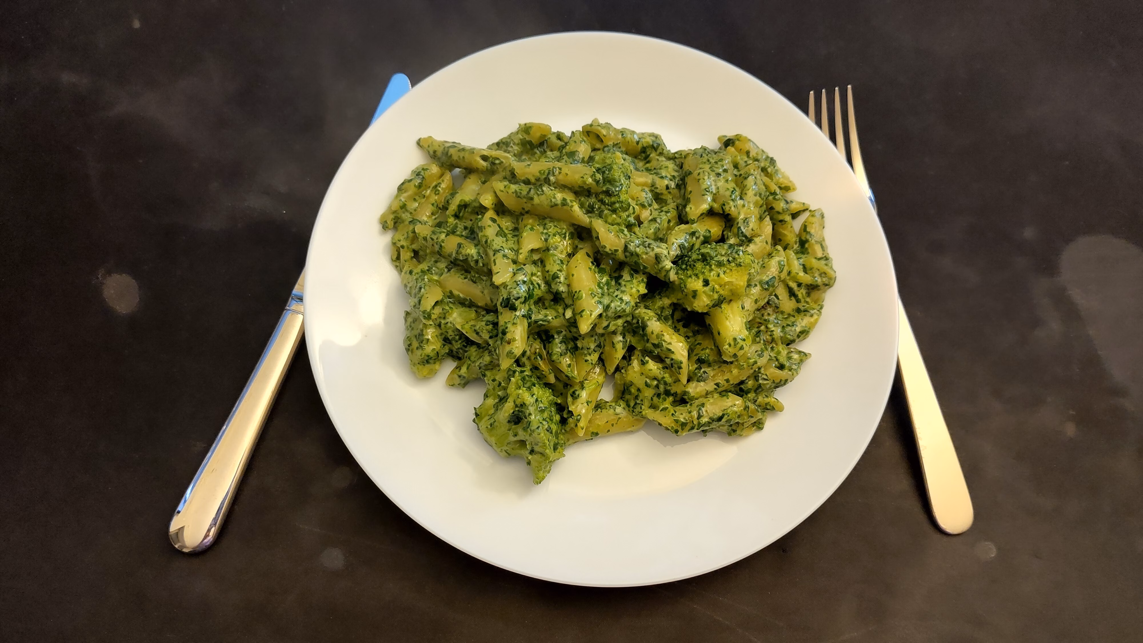A plate with penne and greens