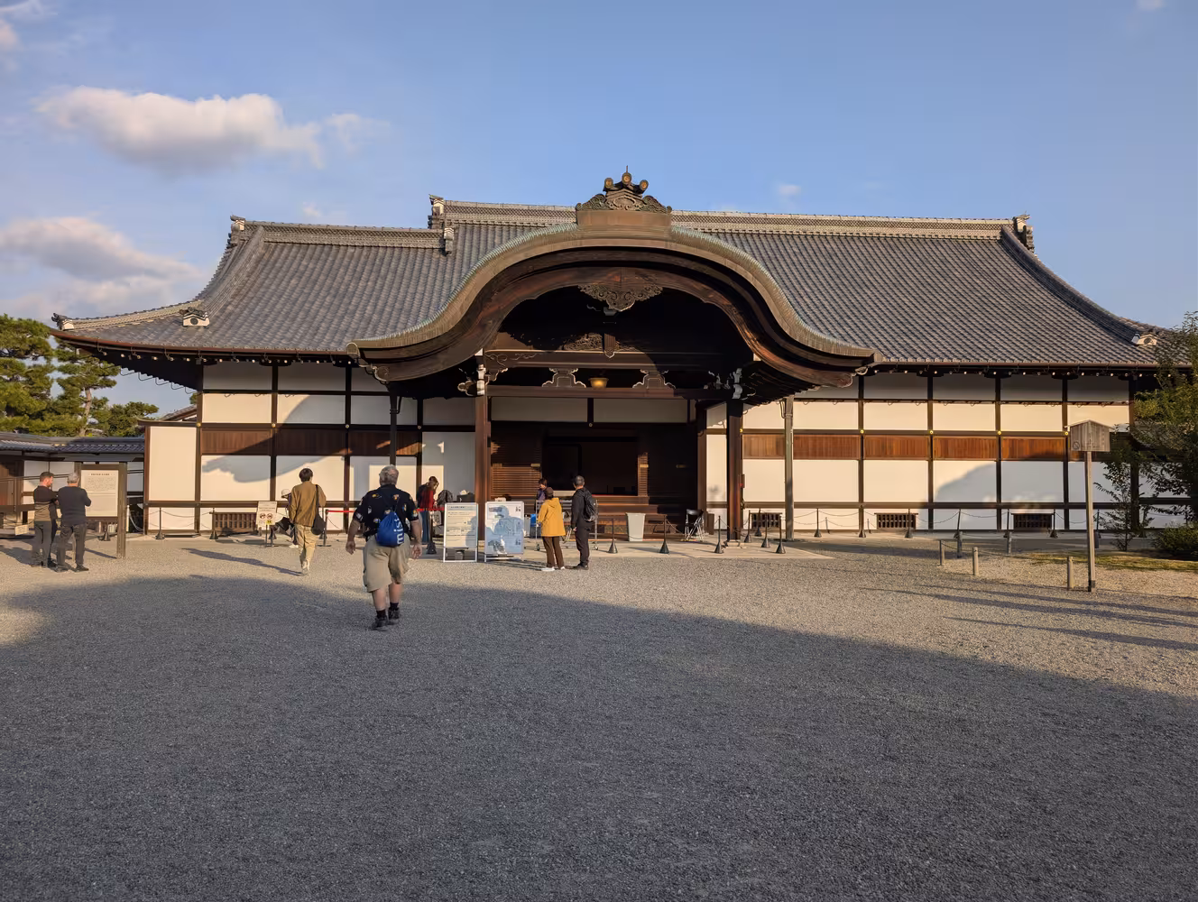 An old and traditional looking building with white walls behind a open place with a ground covered in gravel.
