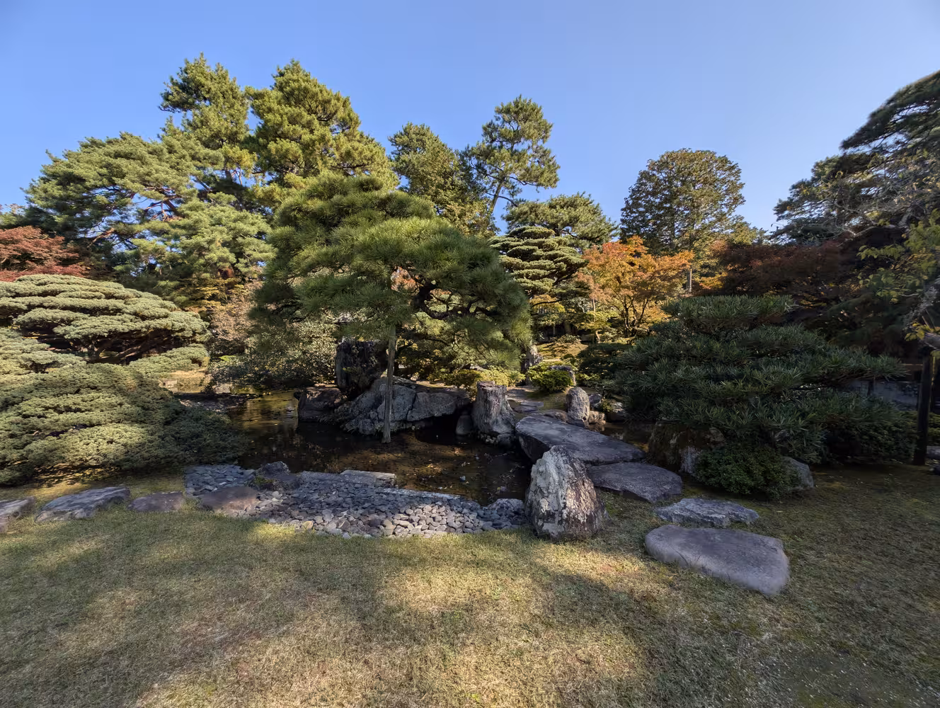 More of the garden, here a small creek with a stone slaps that form a way over it and more trees in the background.
