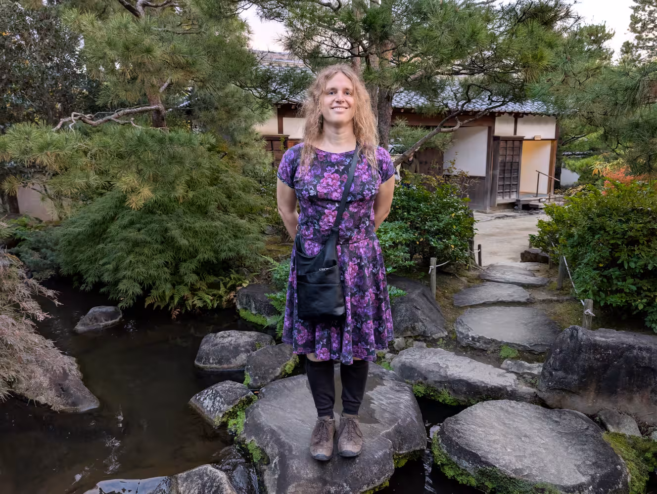 Fiona standing on a stone-slap in the middle of a creek, looking at the camera.