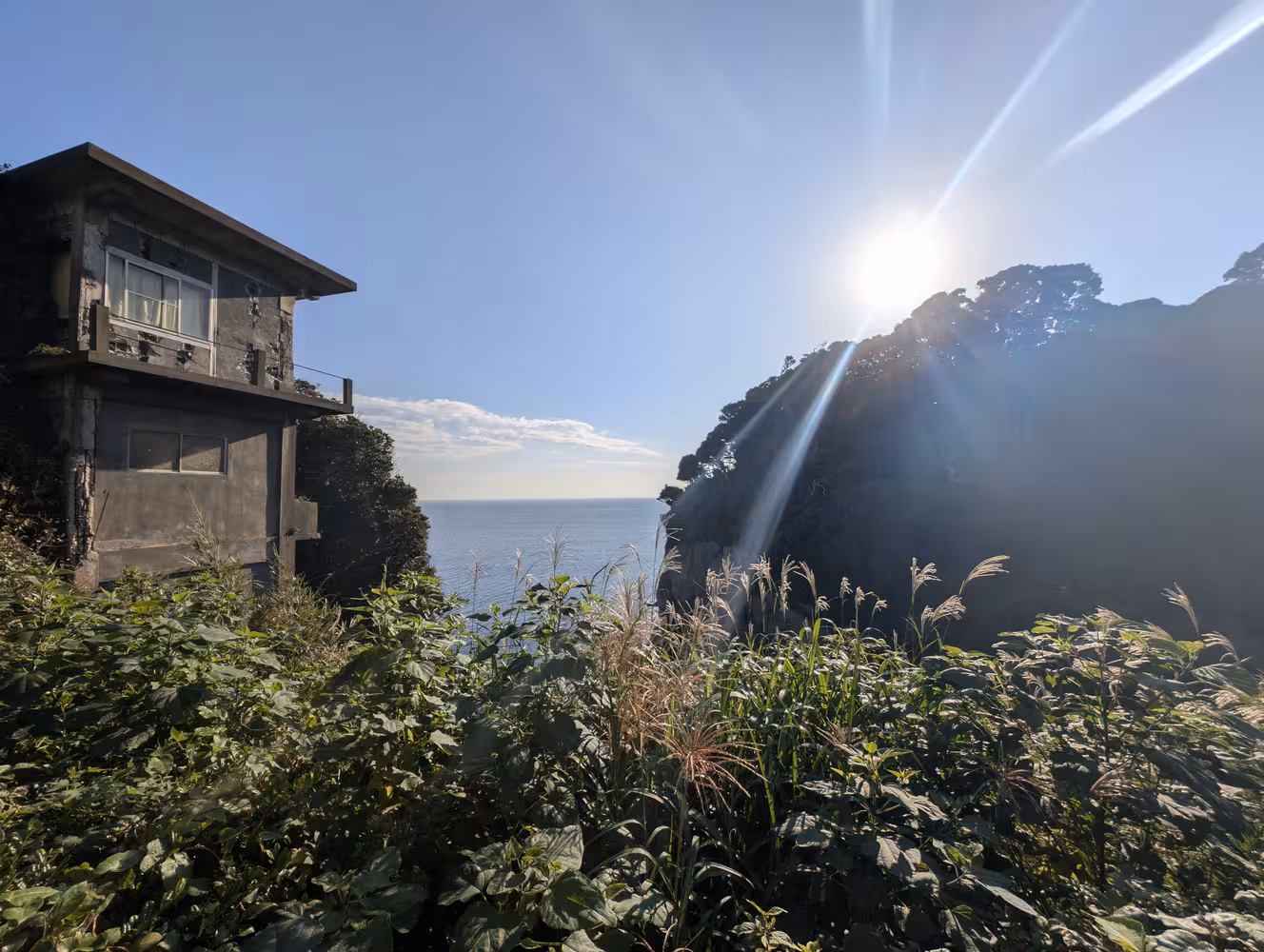 The sun standing right above a large cliff on top of the split in Enoshima Island.